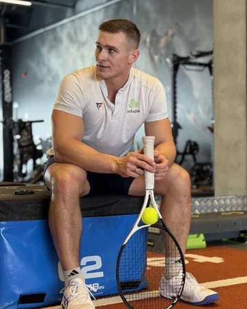 Marius Mėgelaitis sporto salėje su teniso rakete
